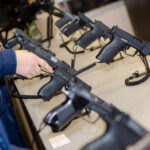 Court Torpedoes Gun Ban For Young Adults A customer examining handguns at a firearms shop display
