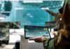 Soldier holding a tablet in a command center with digital maps on screens