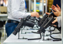 Court Loophole Lets Guns Get Seized? Display of handguns at a firearms exhibition with attendees interacting