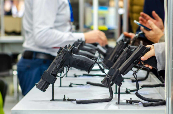 shutterstock1538947526jpg Display of handguns at a firearms exhibition with attendees interacting