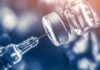 syringe needle drawing liquid from a vaccine vial