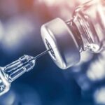 syringe needle drawing liquid from a vaccine vial