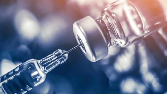 syringe needle drawing liquid from a vaccine vial