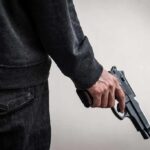 person holding a handgun at their side