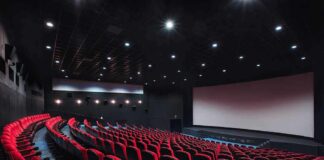 empty movie theater with red seats and large screen