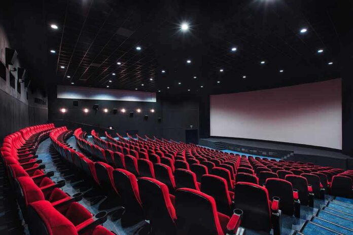 shutterstock_1284521104 empty movie theater with red seats and large screen