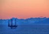 Trump Cheers — Burnham Blinks On Oil? An oil rig in the ocean with a backdrop of mountains during sunset