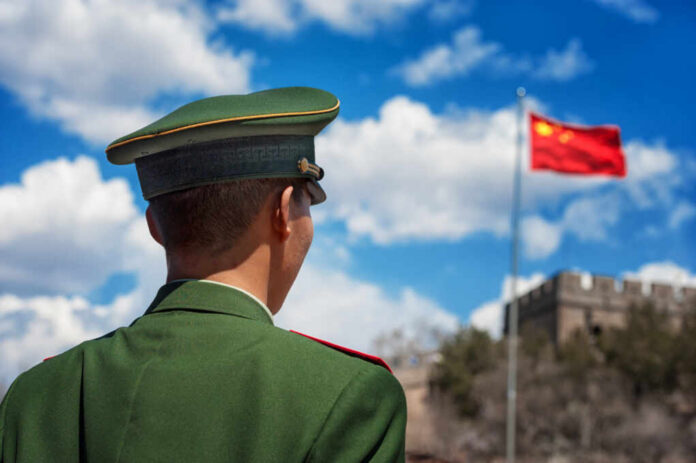 Beijing,-,April,24:,Soldier,Stands,Guard,Near,The,Great A Chinese soldier in uniform standing in front of the Great Wall and the national flag