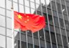 Chinese flag waving against glass office building
