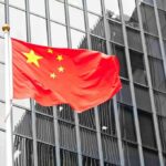 Chinese flag waving against glass office building