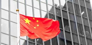 Beijing’s Control Triggers Economic Spiral Chinese flag waving against glass office building