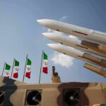Missile launchers on a military vehicle with flags in the background