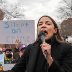 woman speaking into a microphone at an outdoor protest