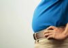 Congress Erupts Over ‘Male’ Pregnancy Claim Person in a blue shirt with hands on hips, showcasing a prominent belly