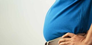 Congress Erupts Over ‘Male’ Pregnancy Claim Person in a blue shirt with hands on hips, showcasing a prominent belly