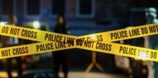 Strangled For Minutes—Then a Cold Cover-Up Police tape marking a crime scene with blurred figures in the background