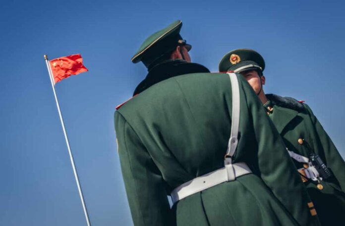 Two Chinese soldiers in military uniforms with a flag in the background