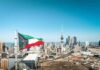 Kuwait flag waving over a city skyline with modern buildings