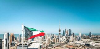 Kuwait flag waving over a city skyline with modern buildings