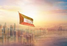 Kuwait flag flying over a modern city skyline at sunrise