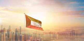 Kuwait flag flying over a modern city skyline at sunrise