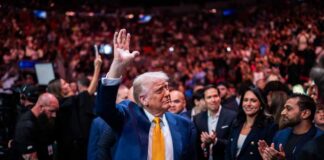 102 Alerts Ignored Before Trump Attack A man in a blue suit with a yellow tie waves to a cheering crowd