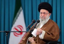 Warren Aide Praises Iran’s Hardliner A hand resting on a coffin adorned with white flowers during a funeral