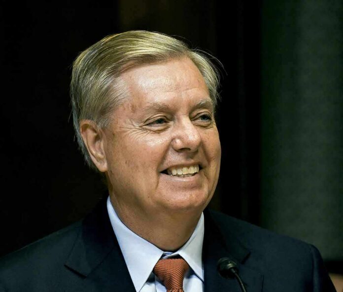 smiling man in suit and tie speaking at a microphone