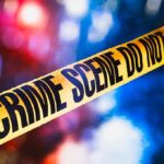 yellow crime scene tape with blurred police lights