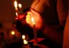 Weekend Bloodshed: What Sparked It? Hands holding lit candles in a dark setting
