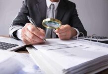 Businessperson examining invoices with a magnifying glass