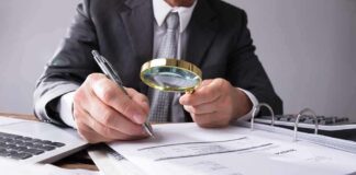 Businessperson examining invoices with a magnifying glass