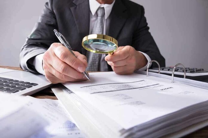 Businessperson examining invoices with a magnifying glass