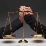 Gold balance scale with two hands arm wrestling behind it