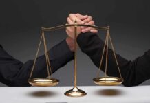 Gold balance scale with two hands arm wrestling behind it