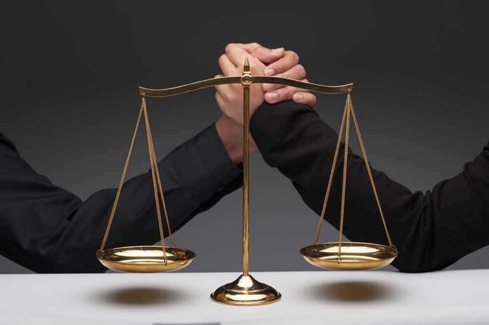 Gold balance scale with two hands arm wrestling behind it