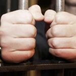 hands gripping prison bars