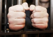 hands gripping prison bars
