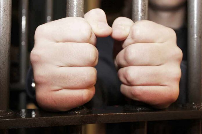 hands gripping prison bars