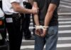 MMA Night Explodes—Arrests Pile Up police officer detains person with hands zip-tied behind back
