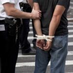 police officer detains person with hands zip-tied behind back