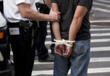 police officer detains person with hands zip-tied behind back