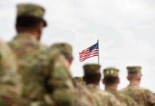 U.S. flag flying above a formation of soldiers in uniform