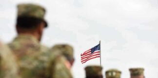 U.S. flag flying above a formation of soldiers in uniform