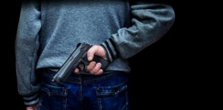 person holding a handgun behind their back