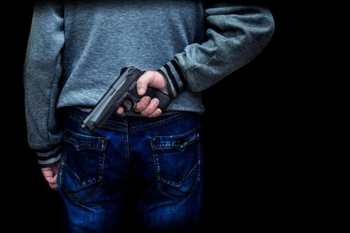 shutterstock_1218320314 person holding a handgun behind their back