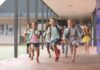 Children running through a school hallway with backpacks