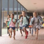 Children running through a school hallway with backpacks