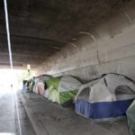 Tents lined up under a concrete overpass