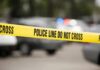 Yellow police line tape at a blurred street scene